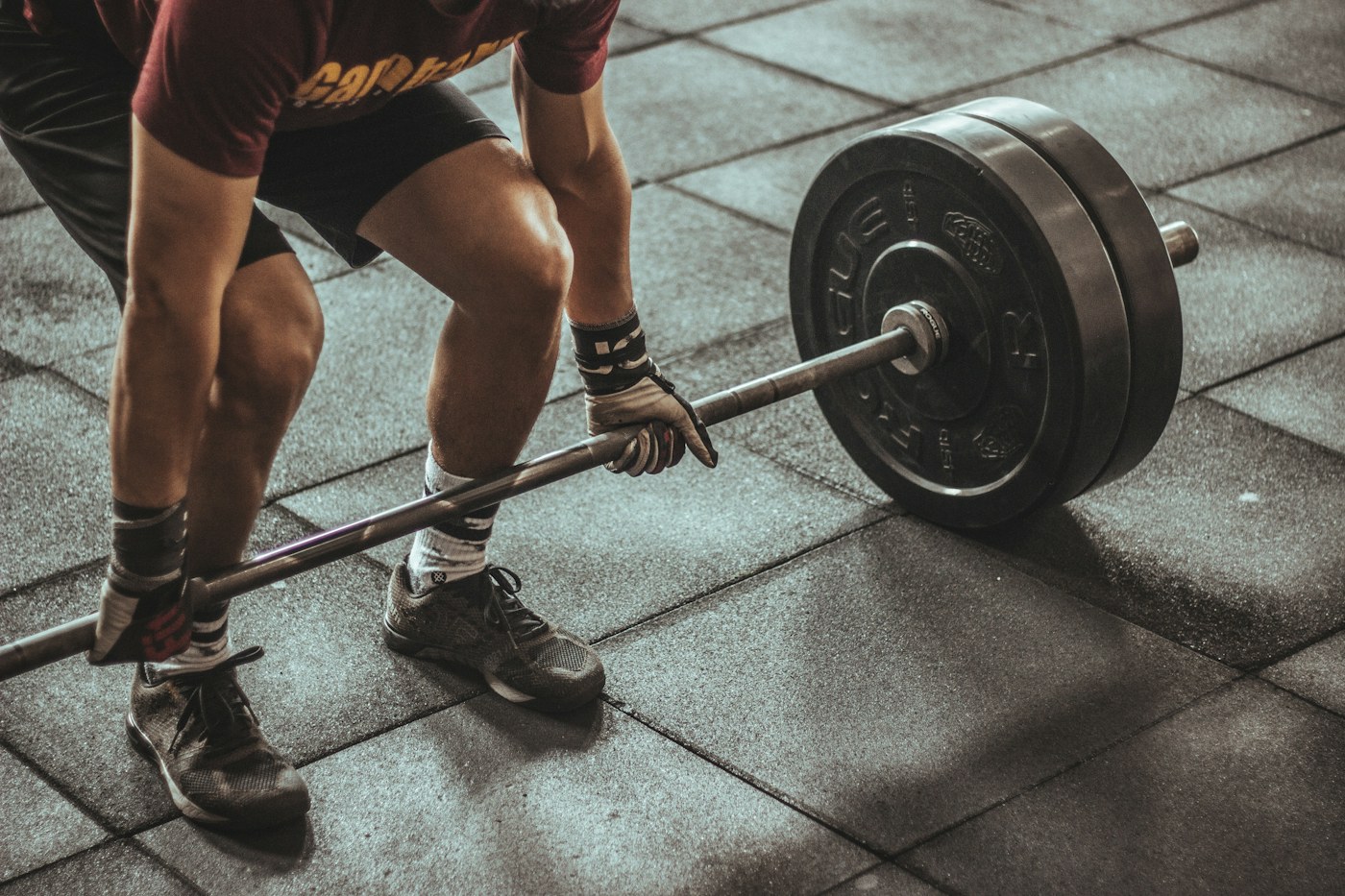 An athlete preparing for a barbell deadlift in a gym